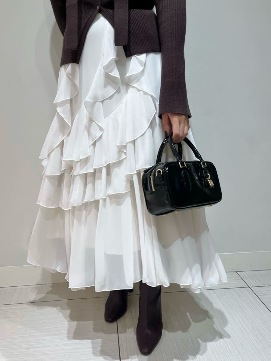 ブラウン系のニット/セーター、ホワイト系のスカート、ブラック系のボストンバッグを着用したレディースの秋コーディネートの5枚目の写真