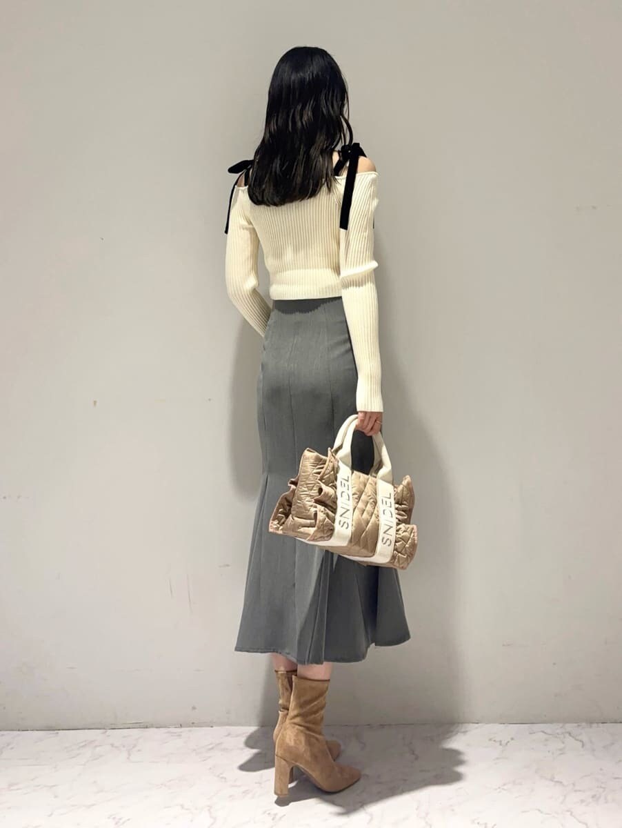 ホワイト系のニット/セーター、グレー系のスカート、ベージュ系のハンドバッグを着用したレディースの秋コーディネートの2枚目の写真