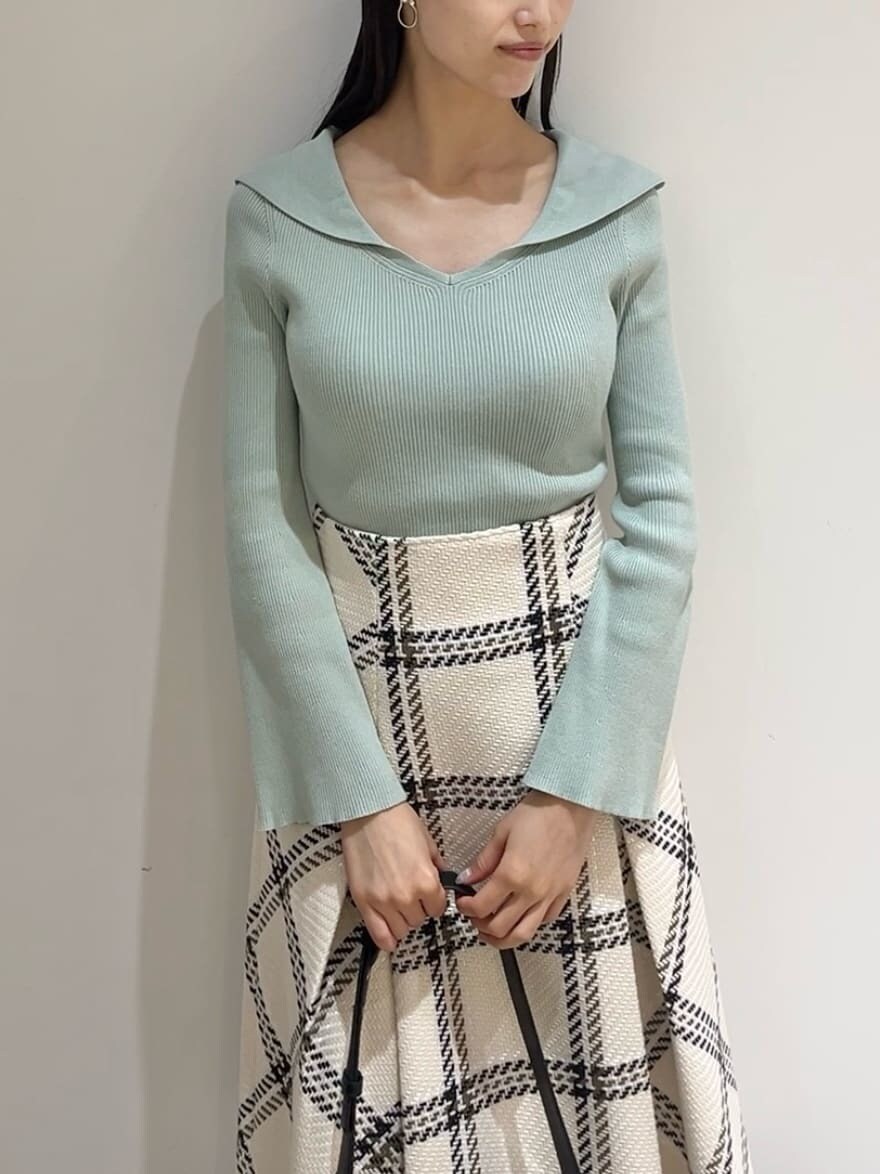 グリーン系のニット/セーター、ホワイト系のスカート、ブラック系のブーツを着用したレディースの秋コーディネートの2枚目の写真