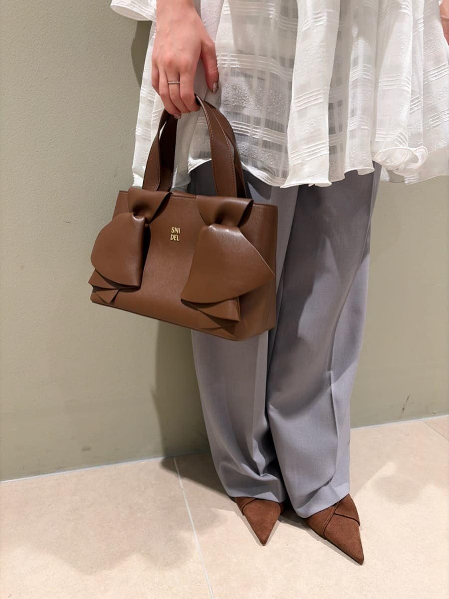 グレー系のスラックス、ホワイト系のワンピース、ブラウン系のパンプスを着用したレディースの春コーディネートの6枚目の写真