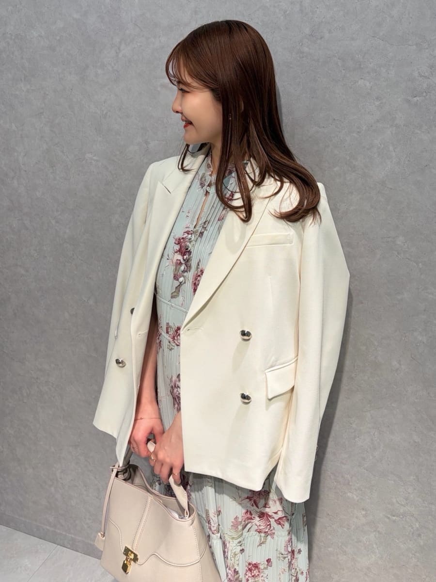 ホワイト系のテーラードジャケット、グリーン系のワンピース、ベージュ系のハンドバッグを着用したレディースの春コーディネートの3枚目の写真