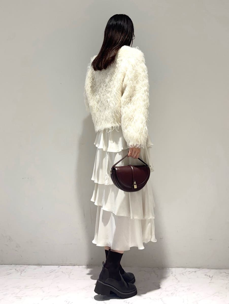 ホワイト系のカーディガン/ボレロ、ホワイト系のスカート、ブラウン系のハンドバッグを着用したレディースの秋コーディネートの2枚目の写真