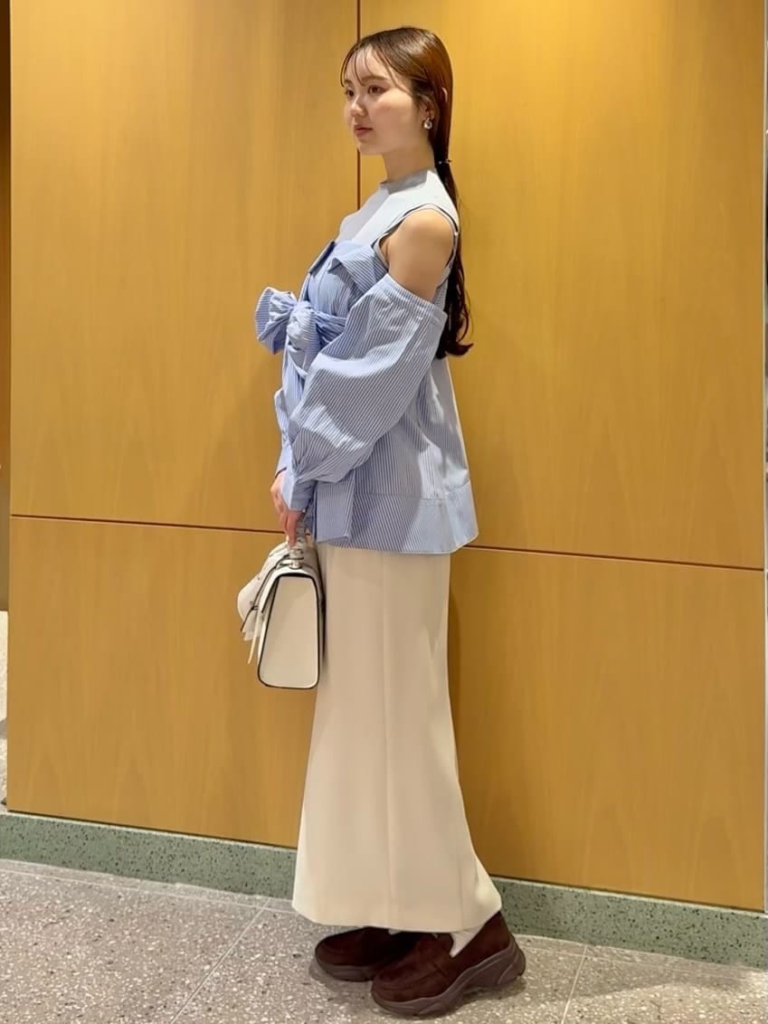 ホワイト系のスカート、ブルー系のニット/セーター、ベージュ系のハンドバッグを着用したレディースの冬コーディネートの2枚目の写真