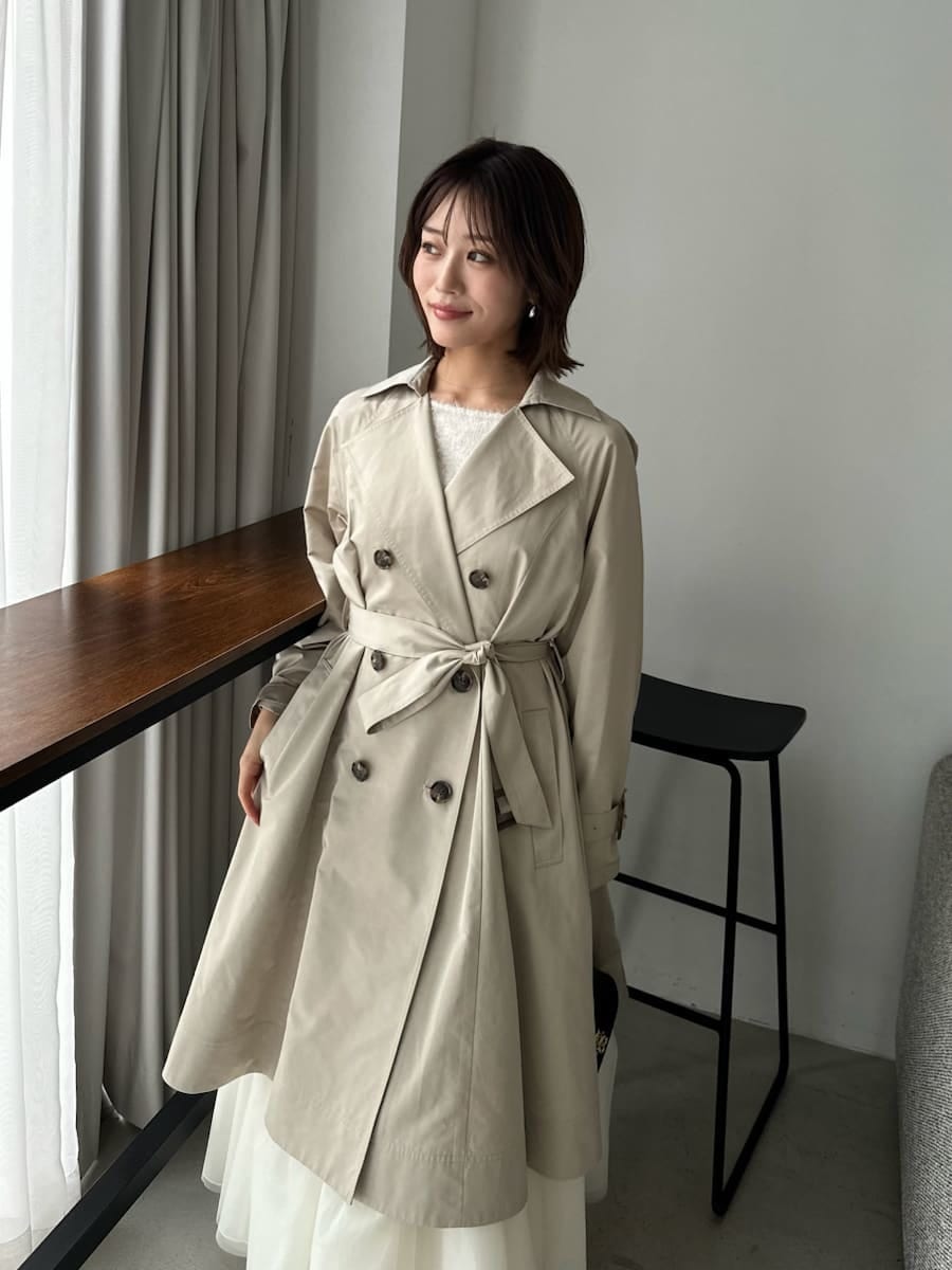 ベージュ系のトレンチコート、ベージュ系のワンピース、ブラック系のショルダーバッグを着用したレディースの春コーディネートの2枚目の写真