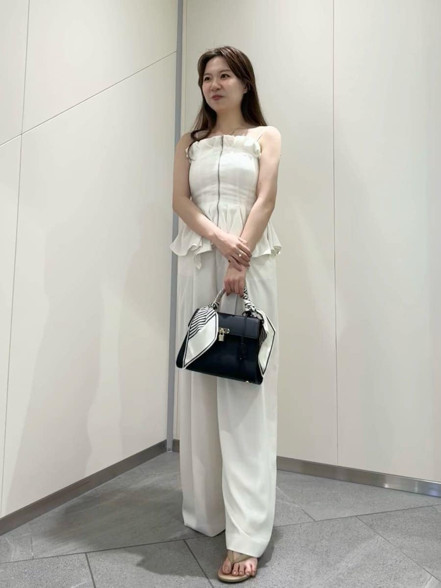 ブラック系のハンドバッグ、ホワイト系のその他パンツ、ホワイト系のその他トップスを着用したレディースの夏コーディネートの2枚目の写真