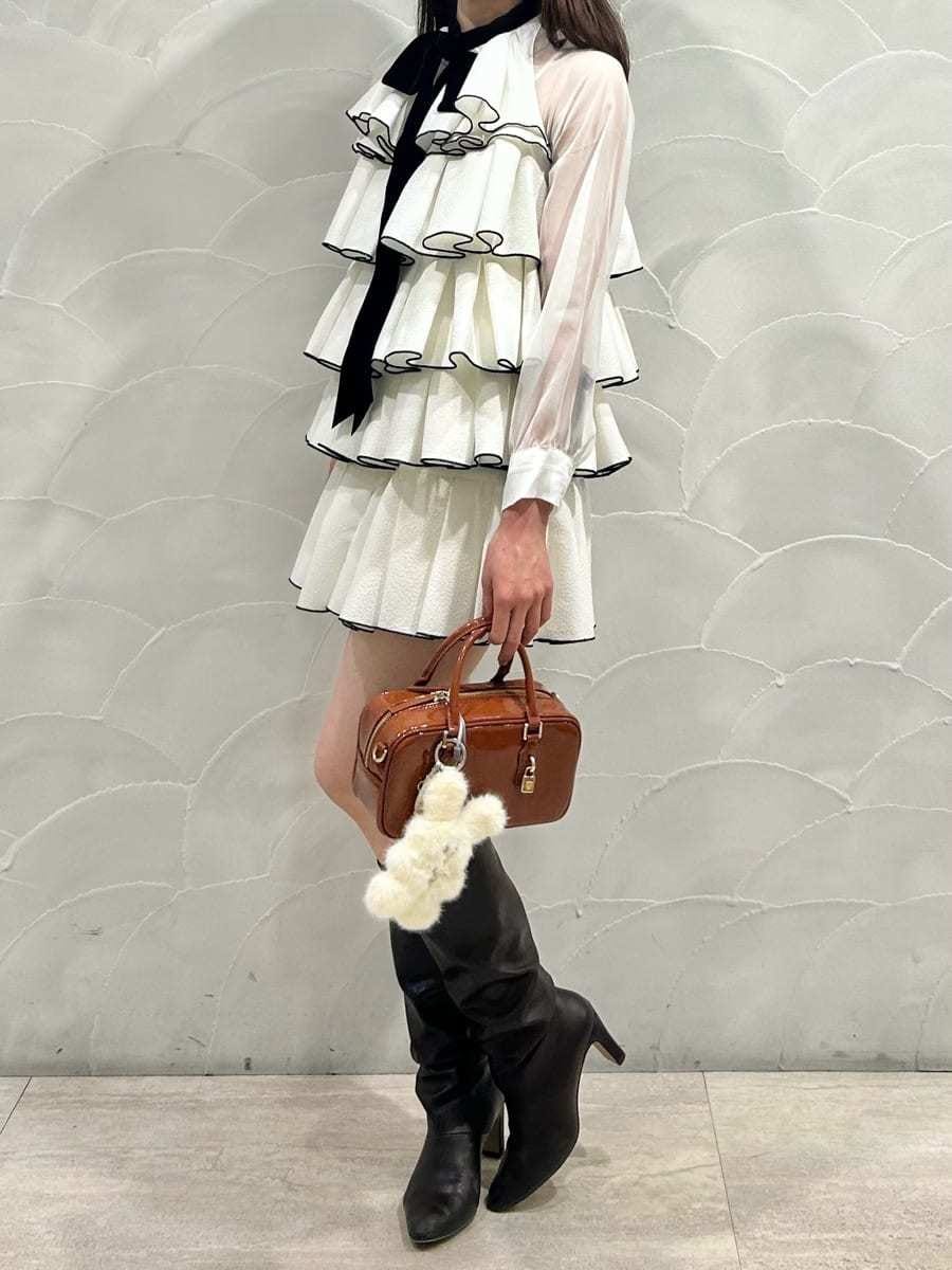 ブラウン系のボストンバッグ、ホワイト系のドレス、イエロー系のキーケース/キーアクセサリーを着用したレディースの冬コーディネートの5枚目の写真
