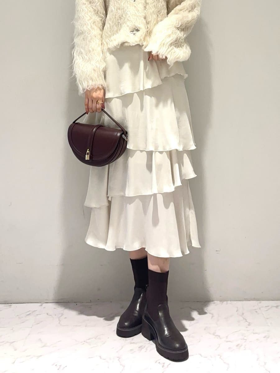 ホワイト系のカーディガン/ボレロ、ホワイト系のスカート、ブラウン系のハンドバッグを着用したレディースの秋コーディネートの5枚目の写真