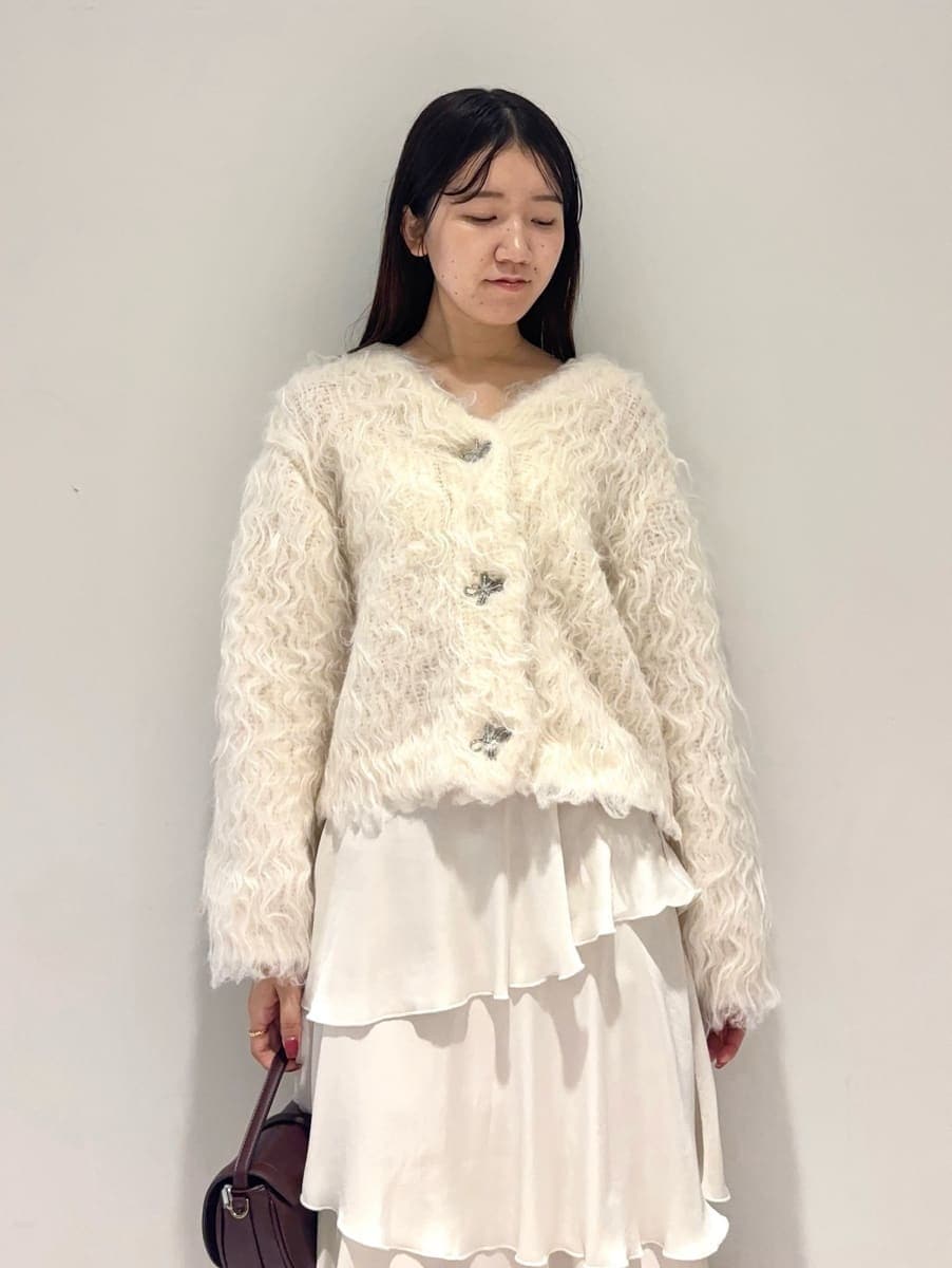 ホワイト系のカーディガン/ボレロ、ホワイト系のスカート、ブラウン系のハンドバッグを着用したレディースの秋コーディネートの4枚目の写真