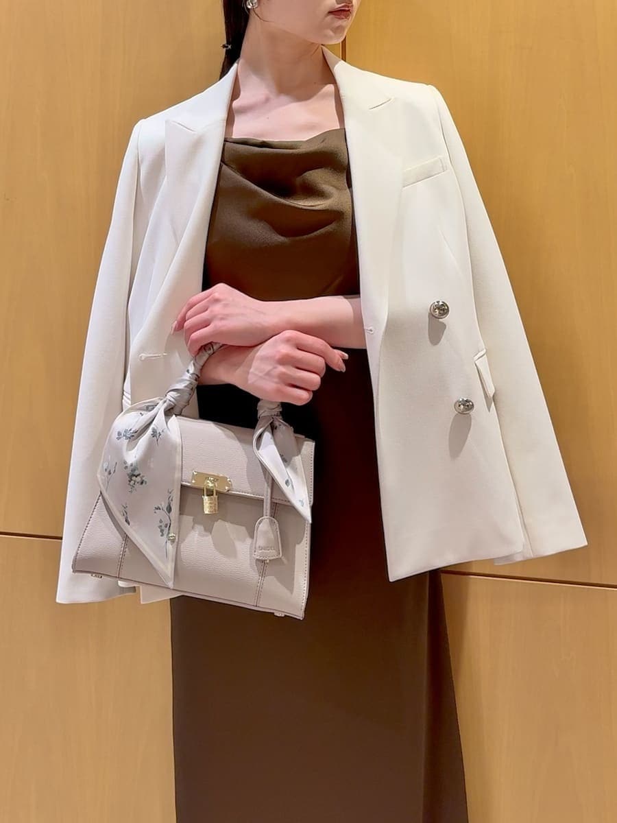 ホワイト系のテーラードジャケット、ブラウン系のパンプス、ベージュ系のハンドバッグを着用したレディースの春コーディネートの9枚目の写真
