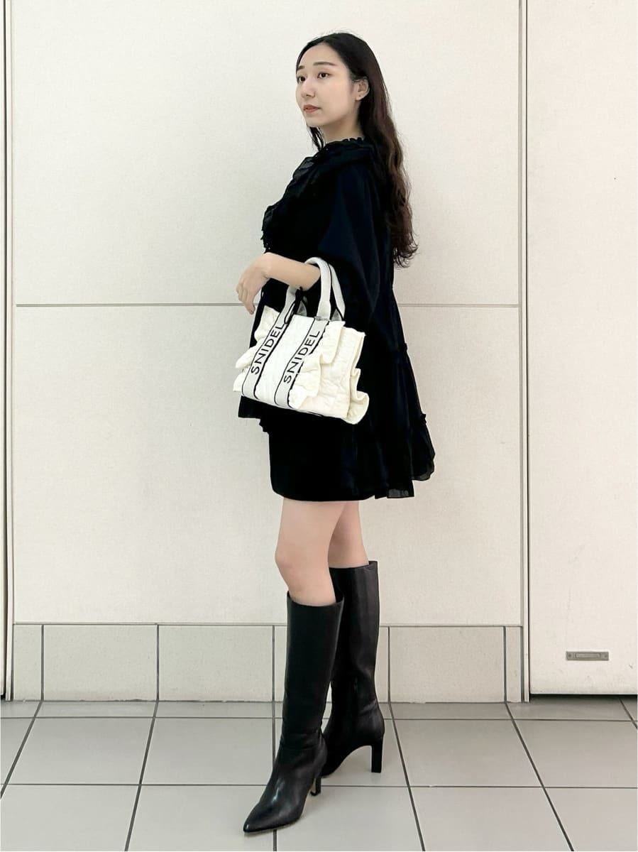 ブラック系のブーツ、ホワイト系のハンドバッグ、ブラック系のスカートを着用したレディースの冬コーディネートの3枚目の写真