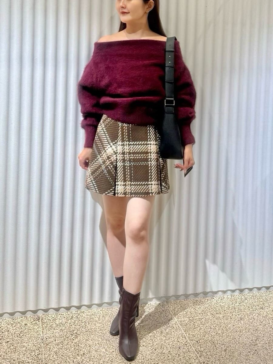 レッド系のニット/セーター、ブラウン系のスカート、レッド系のブーツを着用したレディースの秋コーディネートの3枚目の写真