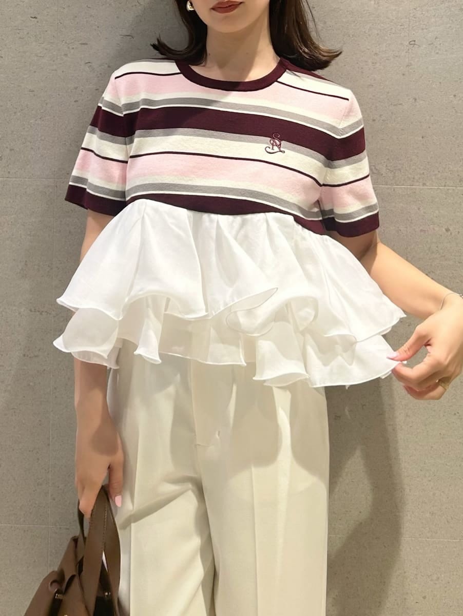 ホワイト系のスラックス、ピンク系のTシャツ/カットソー、ブラウン系のハンドバッグを着用したレディースの春コーディネートの2枚目の写真