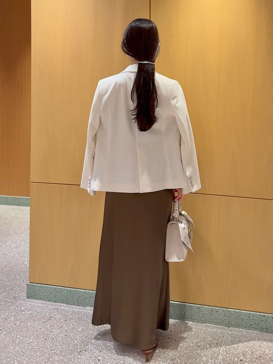 ホワイト系のテーラードジャケット、ブラウン系のパンプス、ベージュ系のハンドバッグを着用したレディースの春コーディネートの3枚目の写真