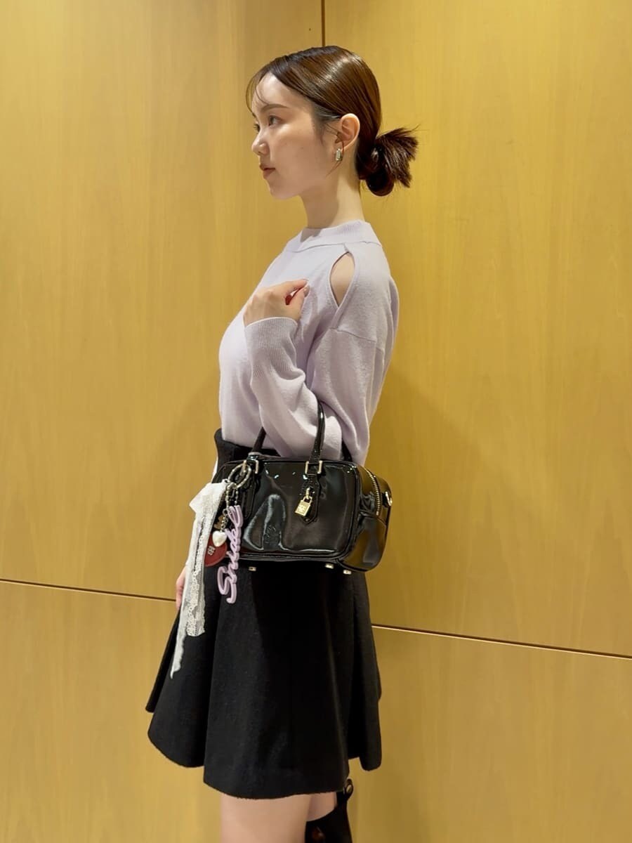 パープル系のニット/セーター、ブラック系のスカート、ブラック系のボストンバッグを着用したレディースの秋コーディネートの2枚目の写真