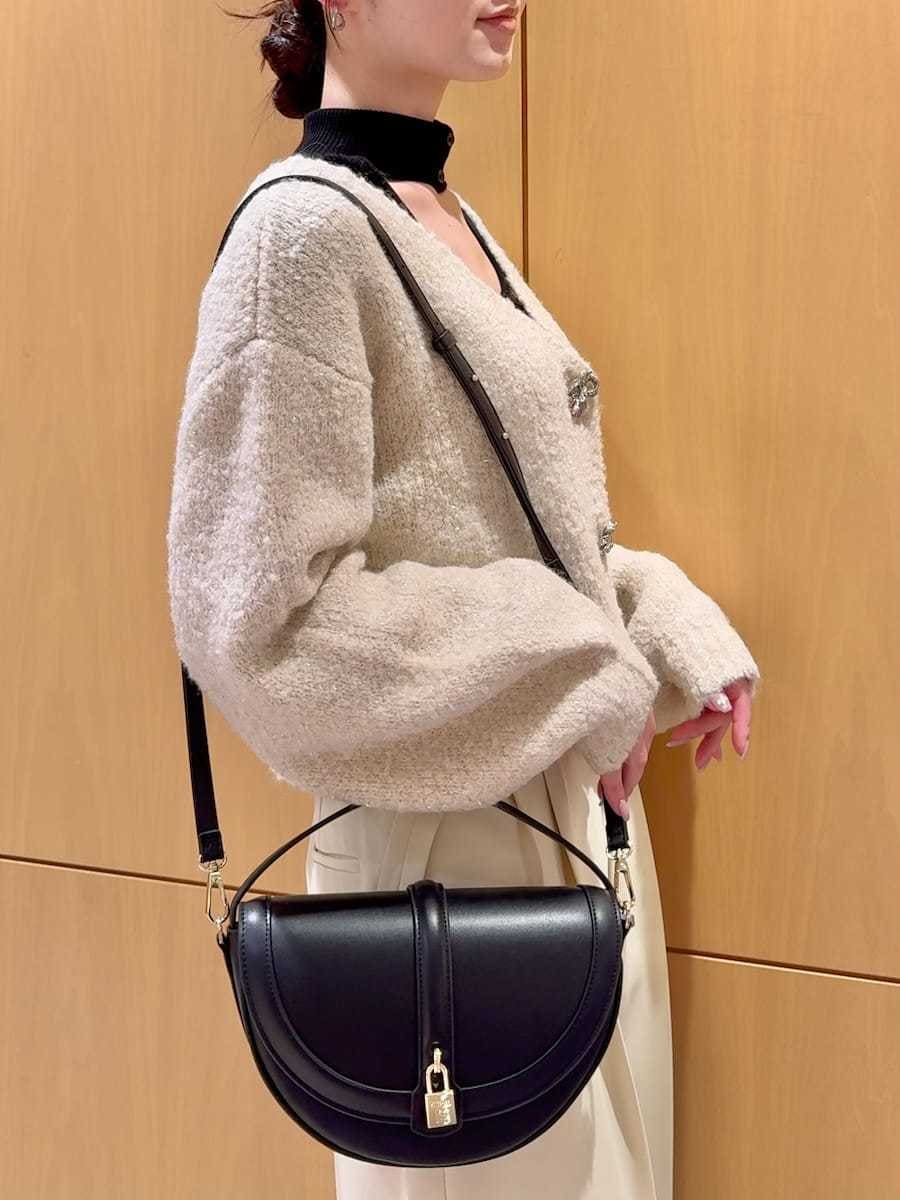 ホワイト系のカーディガン/ボレロ、ブラック系のニット/セーター、ブラック系のブーツを着用したレディースの秋コーディネートの8枚目の写真