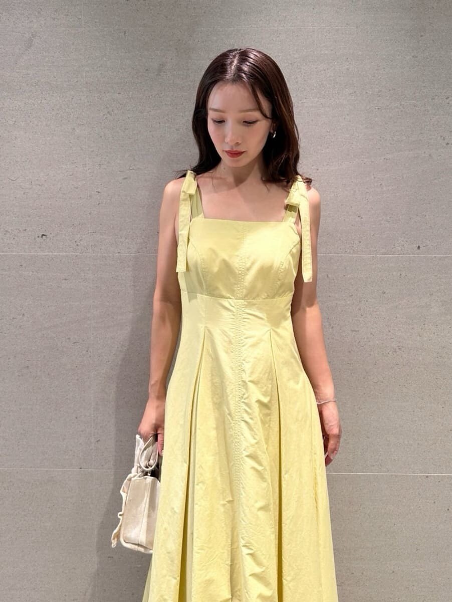 イエロー系のワンピース、ベージュ系のショルダーバッグ、ブラウン系のサンダルを着用したレディースの夏コーディネートの6枚目の写真