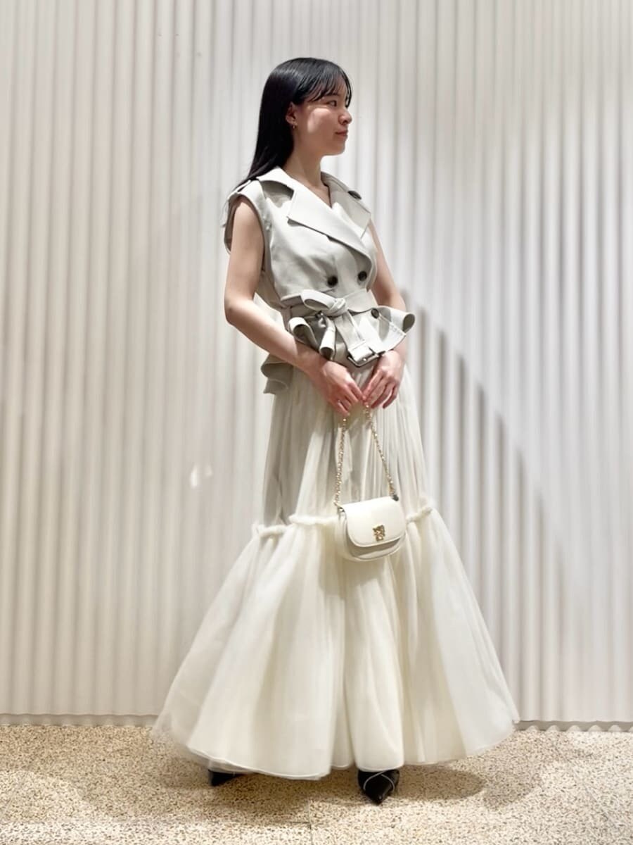 グレー系のワンピース、ブラック系のパンプス、ホワイト系のショルダーバッグを着用したレディースの春コーディネートの2枚目の写真