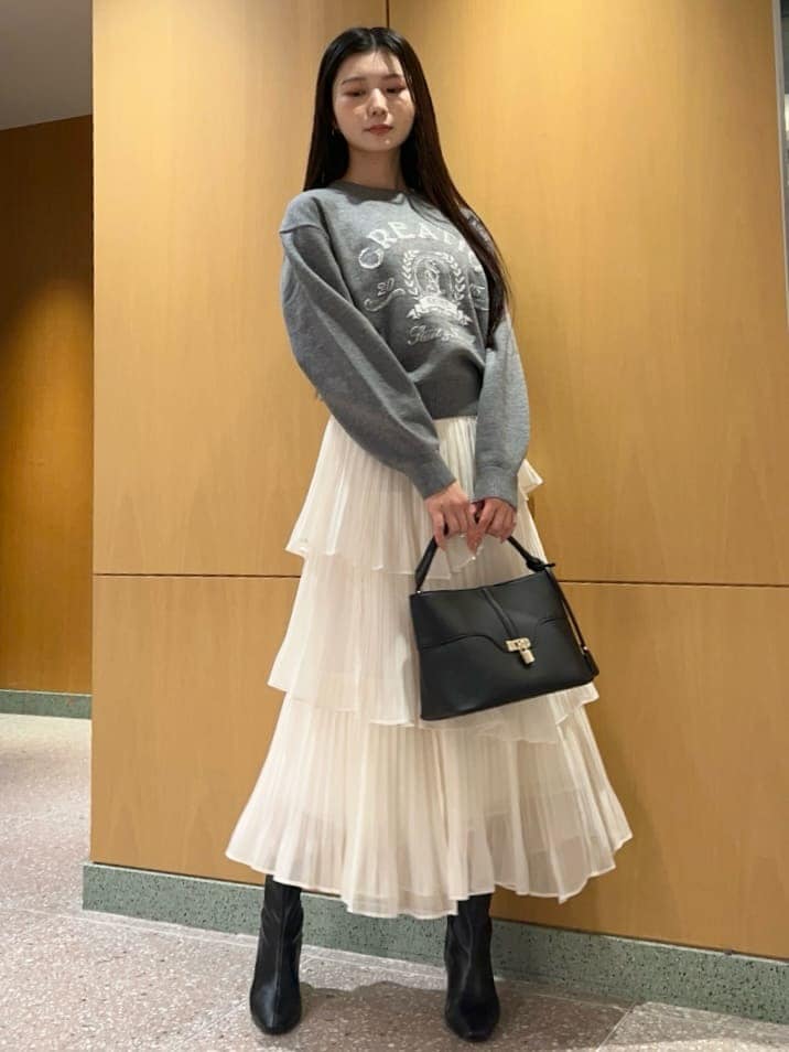 ブラック系のブーツ、ホワイト系のスカート、グレー系のニット/セーターを着用したレディースの秋コーディネートの2枚目の写真