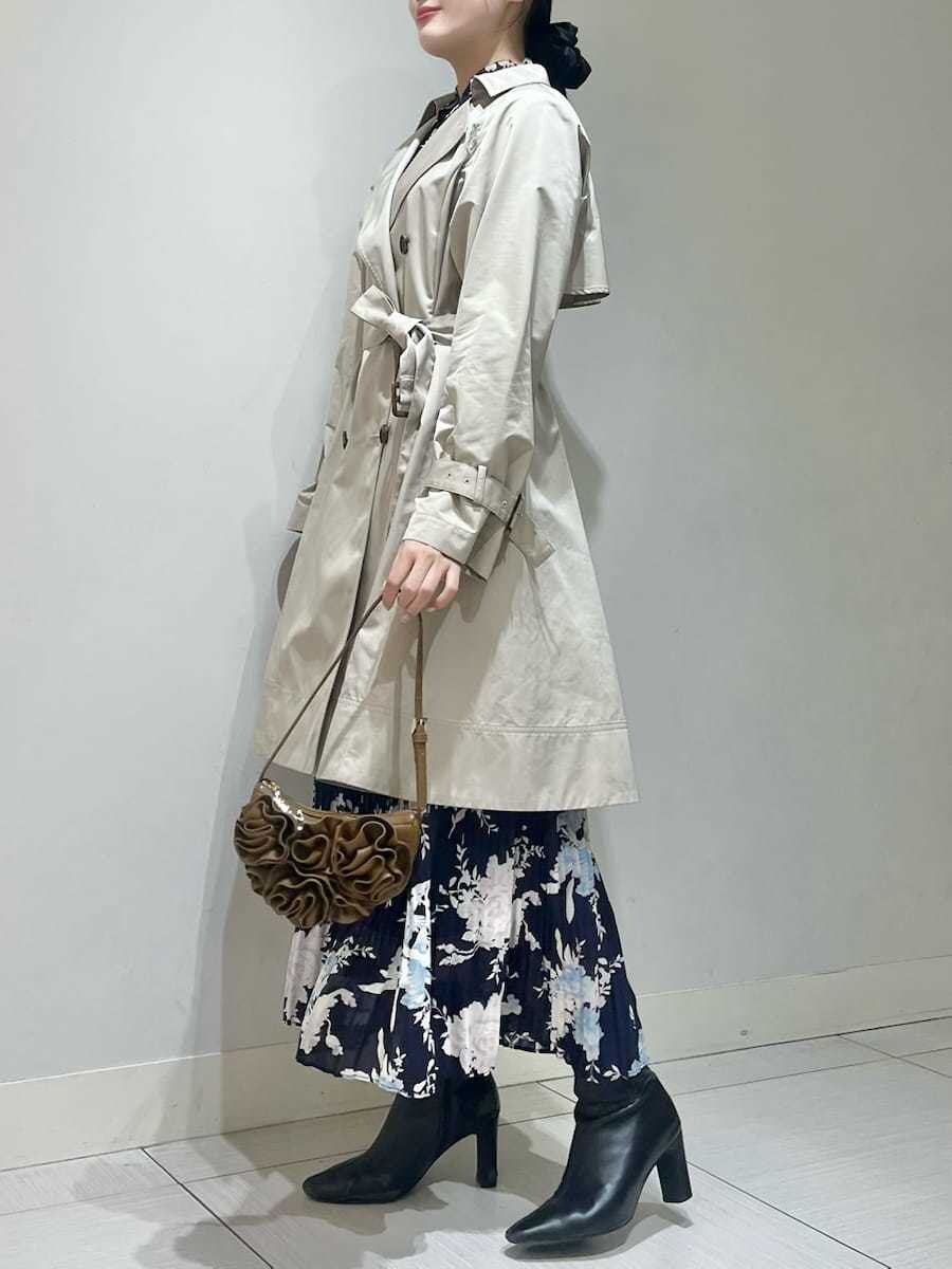 ベージュ系のトレンチコート、ブルー系のワンピース、ブラウン系のハンドバッグを着用したレディースの春コーディネートの2枚目の写真