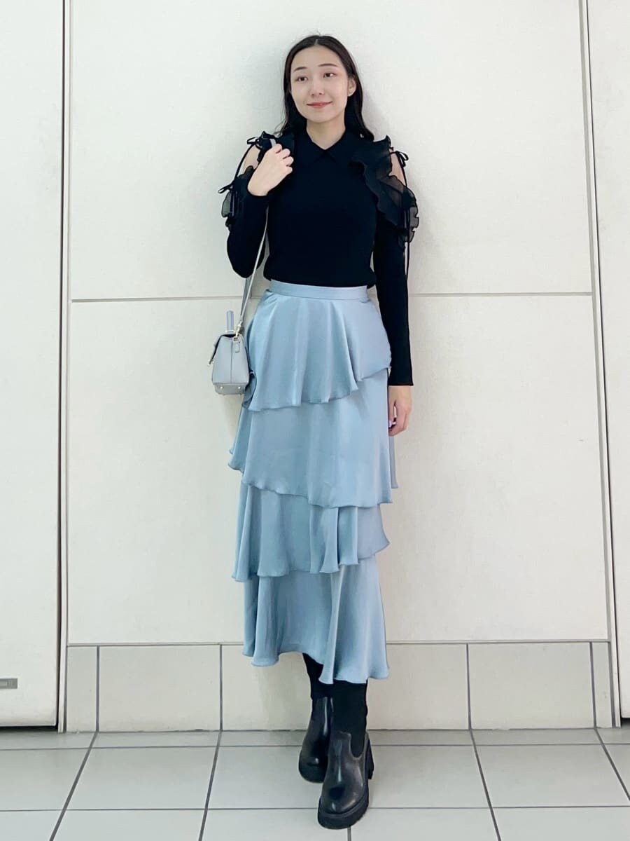 ブラック系のニット/セーター、ブルー系のスカート、ブルー系のショルダーバッグを着用したレディースの秋コーディネートの2枚目の写真