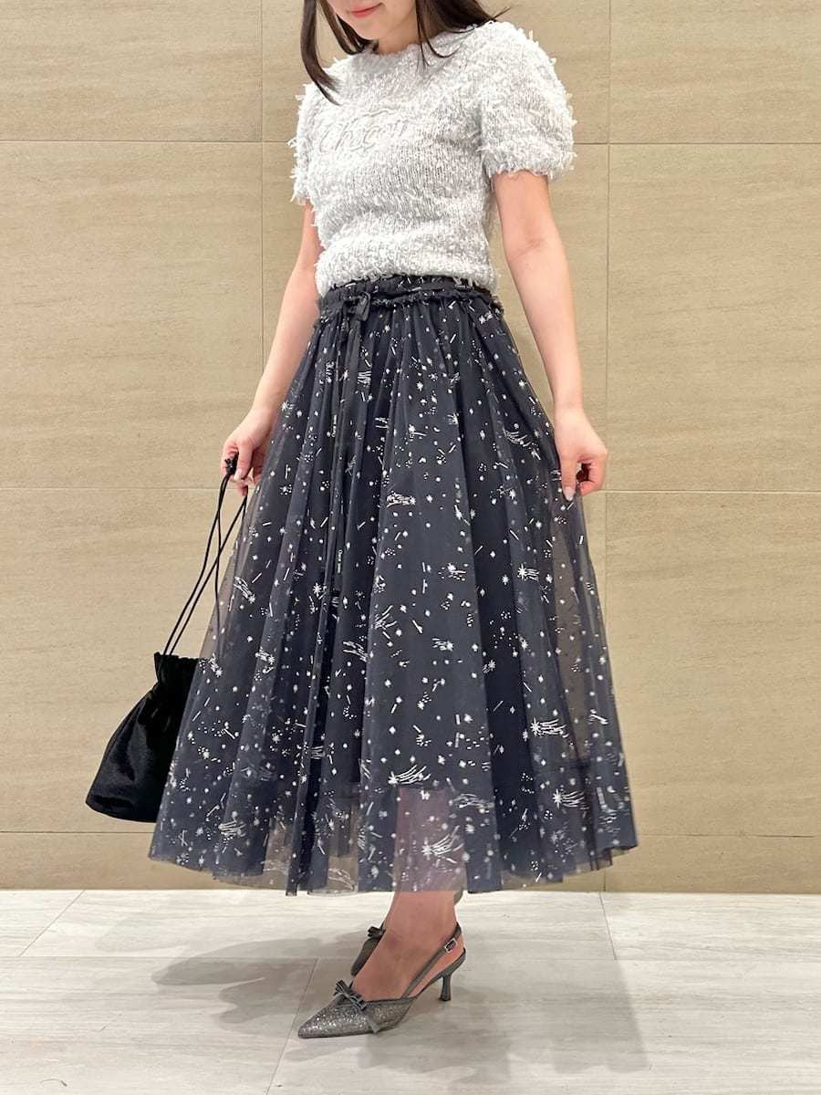 ブルー系のスカート、グレー系のニット/セーター、ブラック系のハンドバッグを着用したレディースの秋コーディネートの4枚目の写真