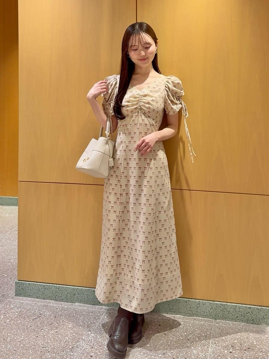 ホワイト系のハンドバッグ、ベージュ系のワンピース、レッド系のカーディガン/ボレロを着用したレディースの冬コーディネートの3枚目の写真