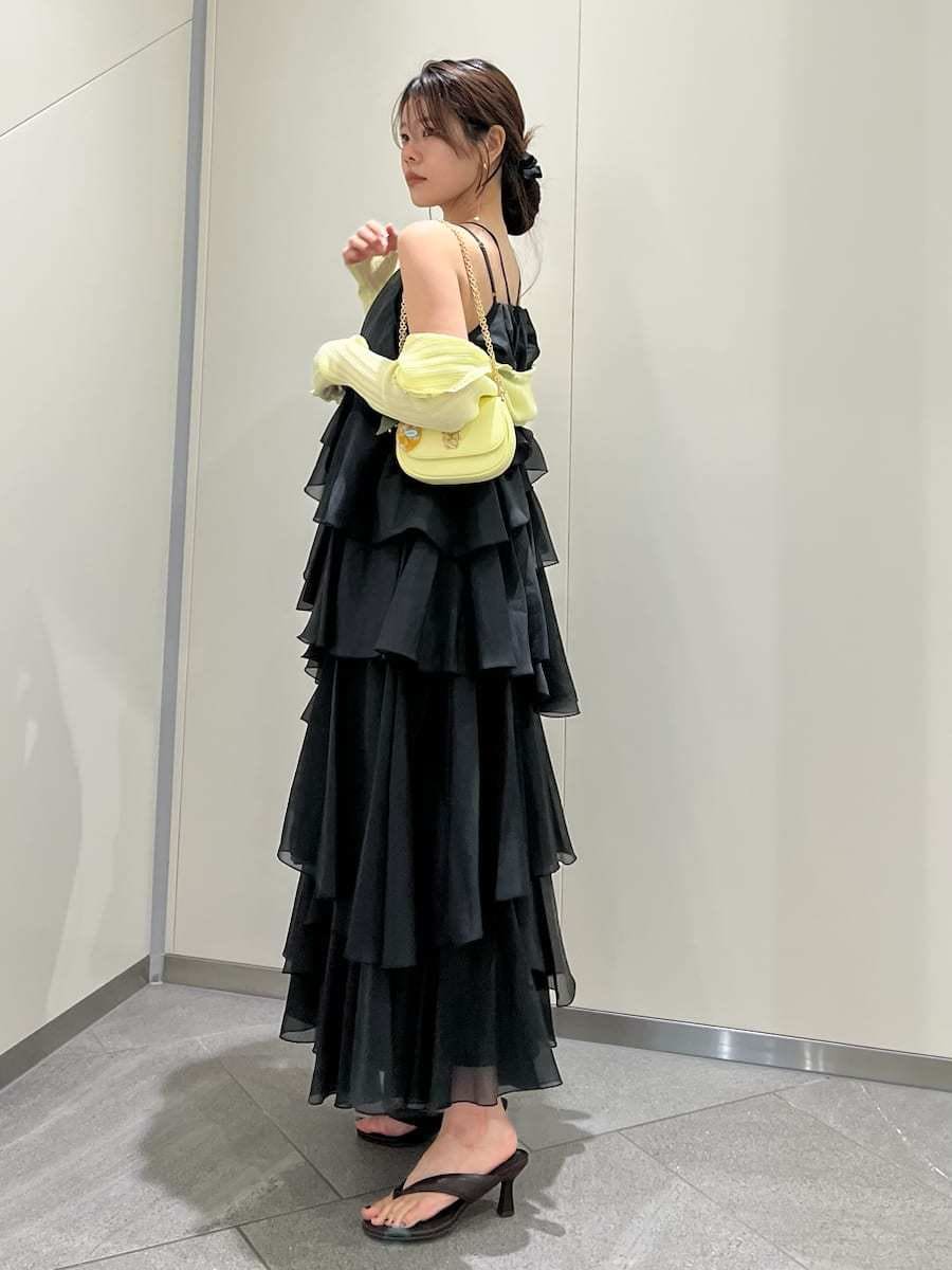 イエロー系のショルダーバッグ、イエロー系のカーディガン/ボレロ、ブラック系のドレスを着用したレディースの夏コーディネートの2枚目の写真