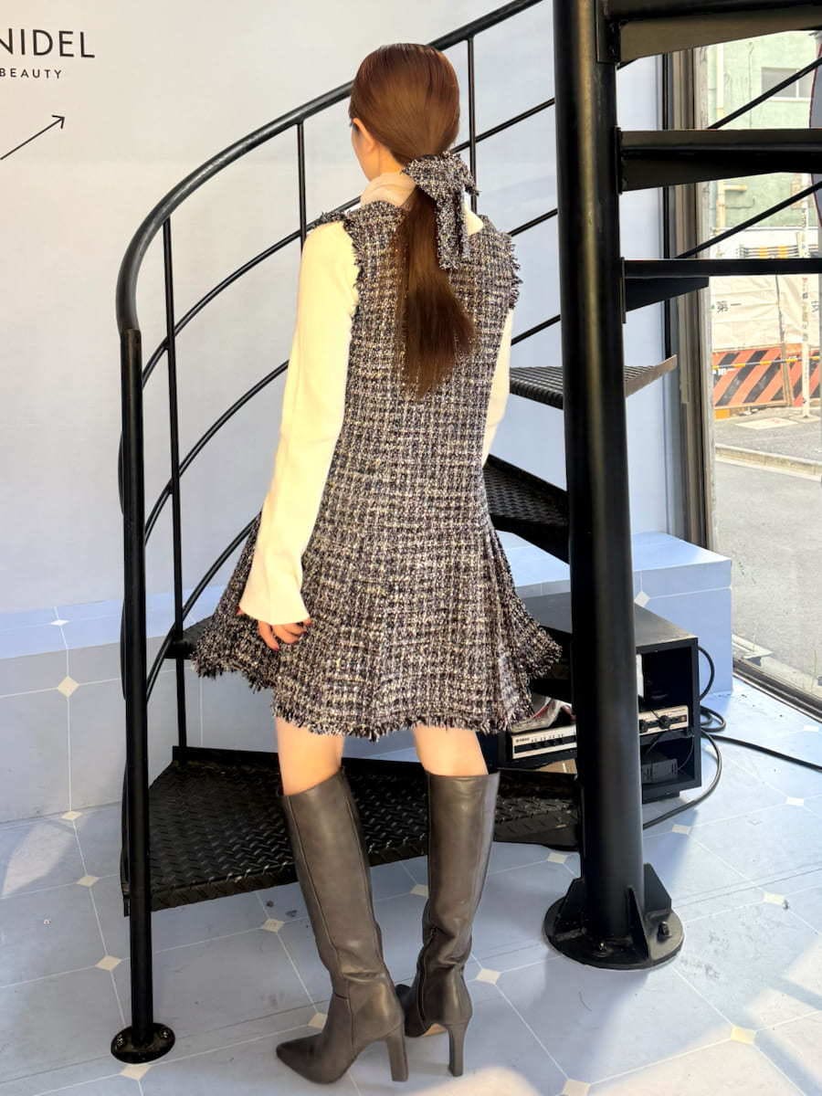 グレー系のブーツ、ブルー系のワンピース、ブラック系のハンドバッグを着用したレディースの冬コーディネートの2枚目の写真