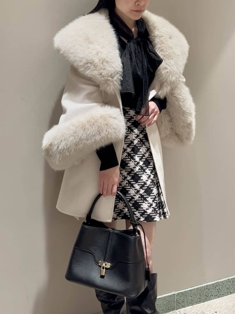 ホワイト系のチェスターコート、ブラック系のその他パンツ、ブラック系のハンドバッグを着用したレディースの冬コーディネートの5枚目の写真