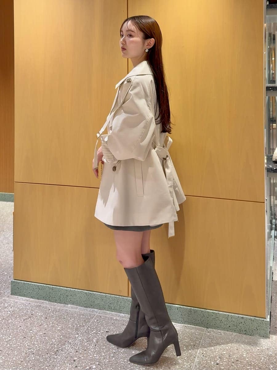 グレー系のブーツ、ホワイト系のトレンチコート、グレー系のワンピースを着用したレディースの冬コーディネートの3枚目の写真