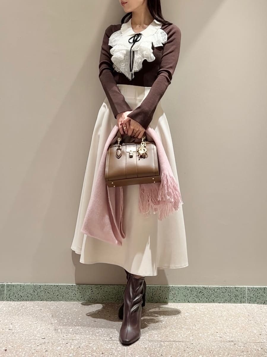 レッド系のブーツ、ブラウン系のニット/セーター、ブラウン系のハンドバッグを着用したレディースの冬コーディネートの2枚目の写真