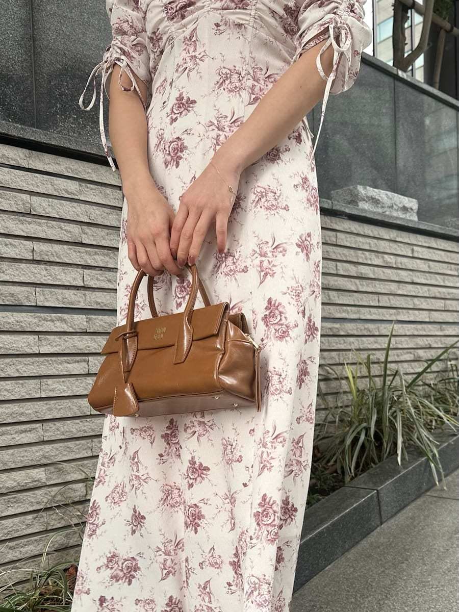 イエロー系のボストンバッグ、ピンク系のワンピースを着用したレディースの冬コーディネートの5枚目の写真