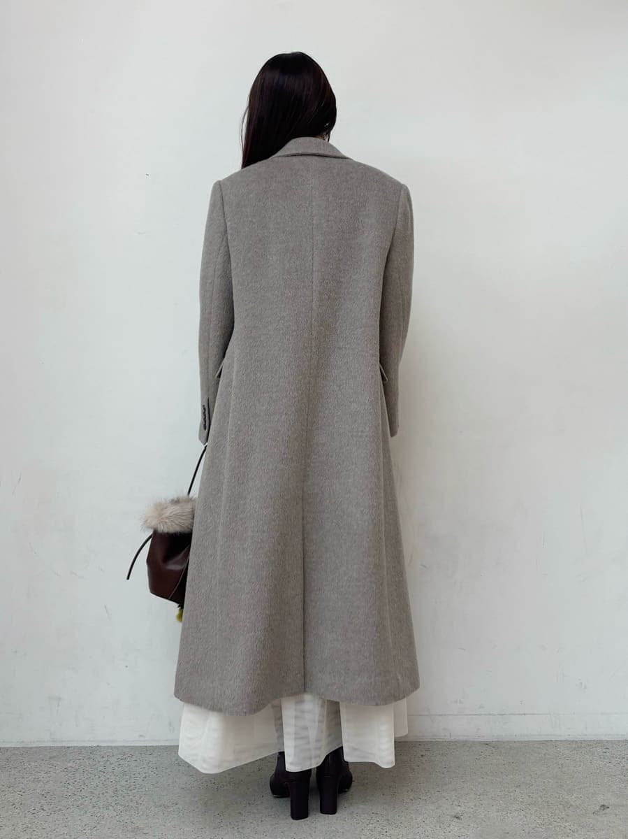 レッド系のブーツ、グレー系のチェスターコート、ホワイト系のスカートを着用したレディースの冬コーディネートの4枚目の写真