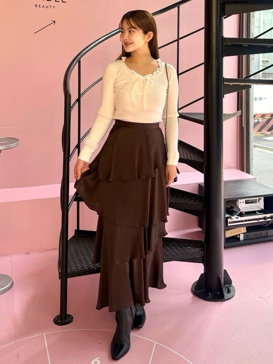 ホワイト系のニット/セーター、ブラウン系のスカート、ブラック系のブーツを着用したレディースの秋コーディネートの2枚目の写真
