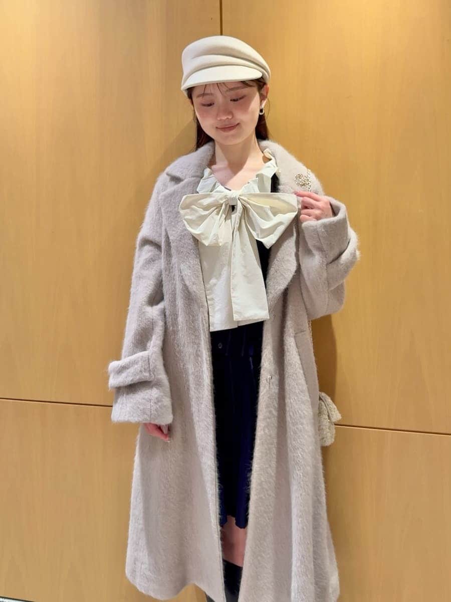 ブラック系のブーツ、ホワイト系のショルダーバッグ、ベージュ系のチェスターコートを着用したレディースの冬コーディネートの2枚目の写真