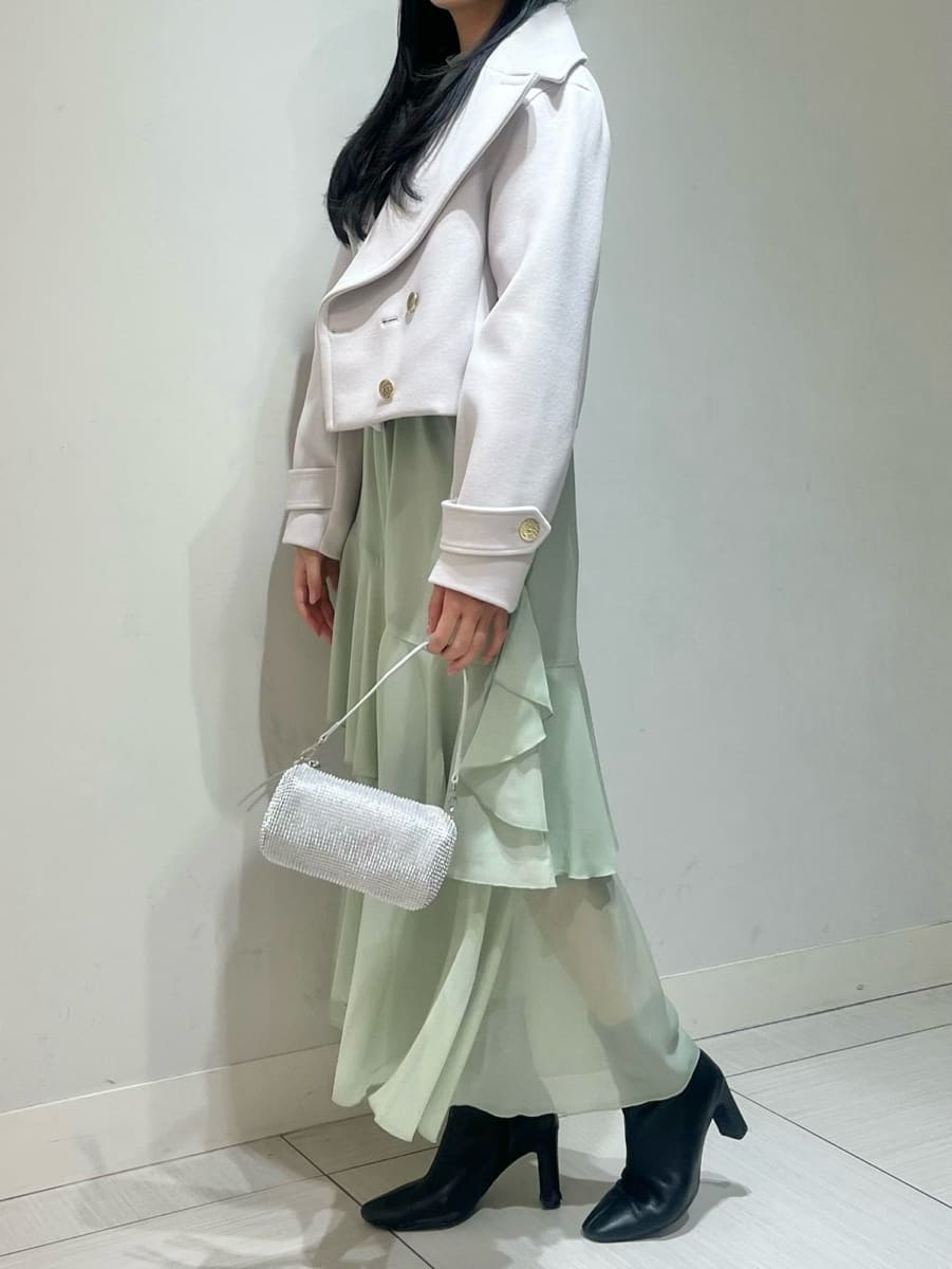 ブラック系のブーツ、ベージュ系のピーコート、グリーン系のワンピースを着用したレディースの冬コーディネートの2枚目の写真