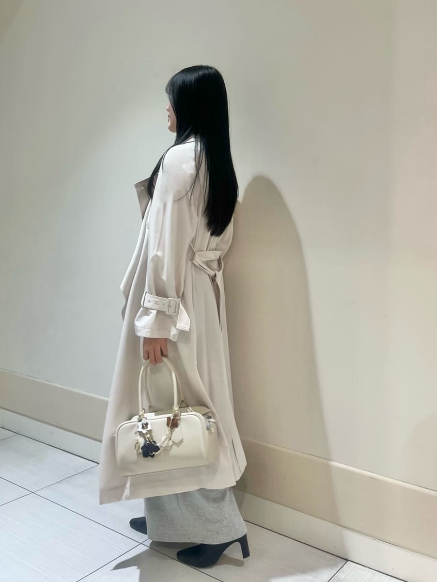 ブラック系のブーツ、ホワイト系のトレンチコート、グレー系のその他パンツを着用したレディースの冬コーディネートの2枚目の写真