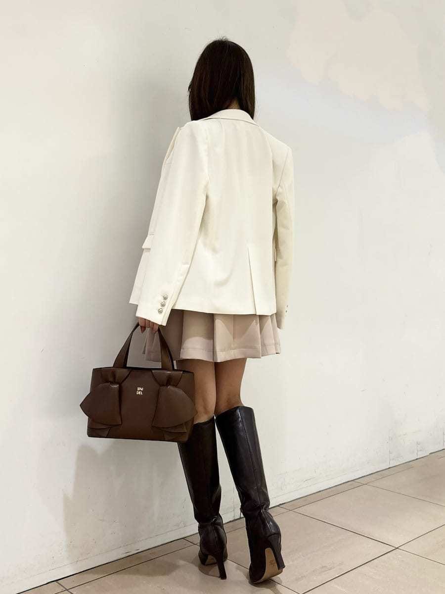 ブラウン系のブーツ、ホワイト系のテーラードジャケット、ベージュ系のスカートを着用したレディースの冬コーディネートの5枚目の写真