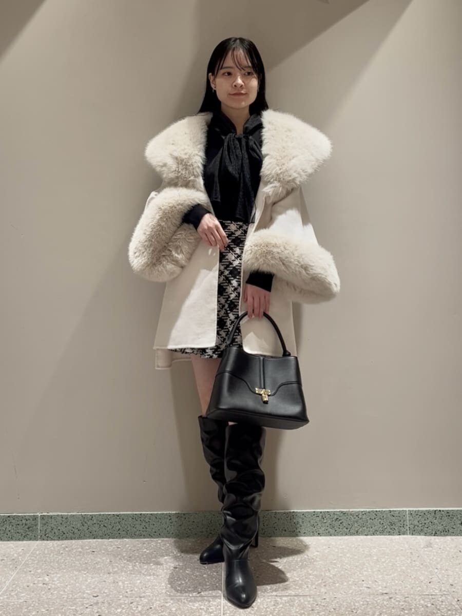 ホワイト系のチェスターコート、ブラック系のその他パンツ、ブラック系のハンドバッグを着用したレディースの冬コーディネートの4枚目の写真