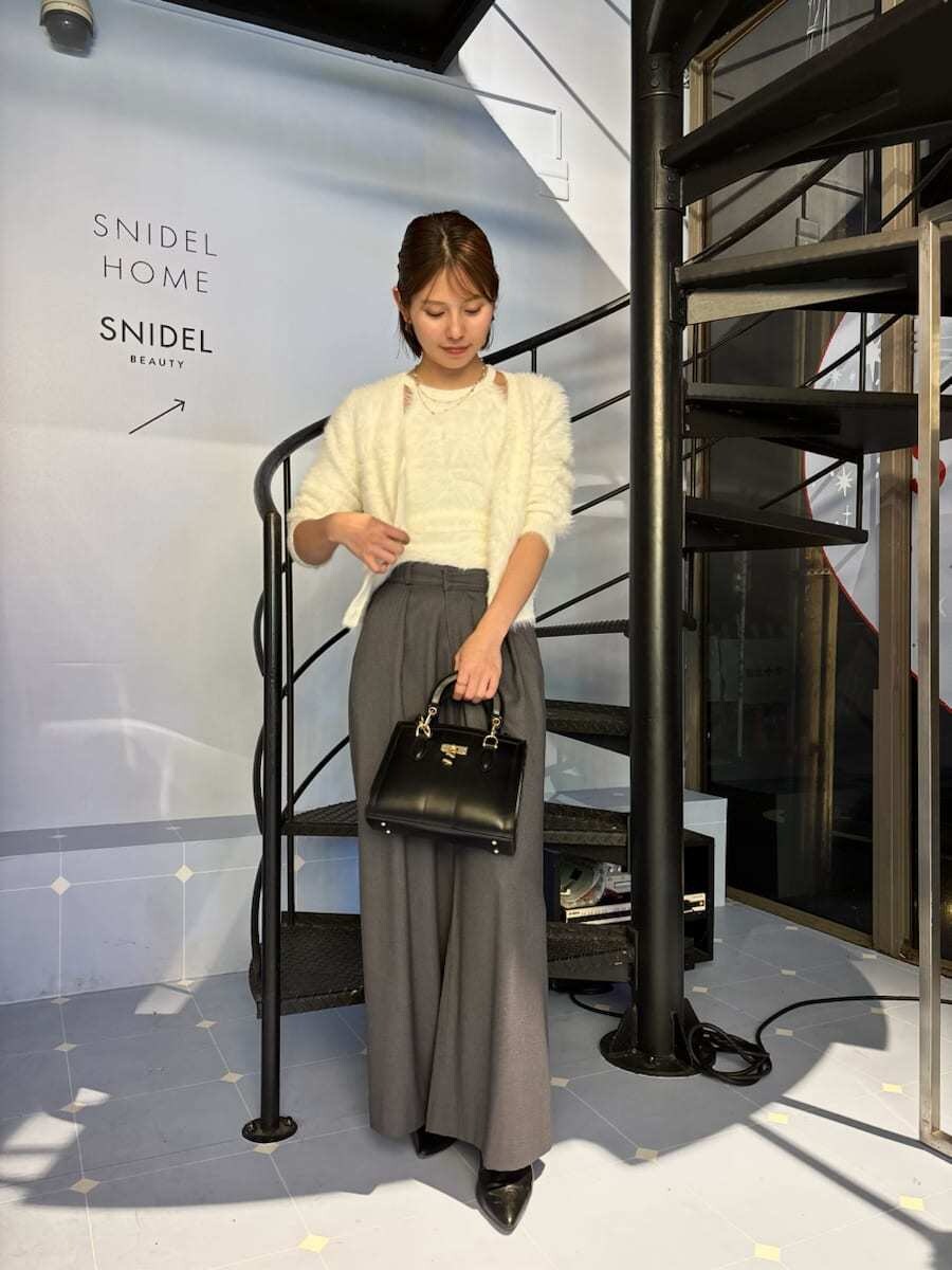 ブラック系のブーツ、ホワイト系のニット/セーター、ブラック系のハンドバッグを着用したレディースの秋コーディネートの2枚目の写真