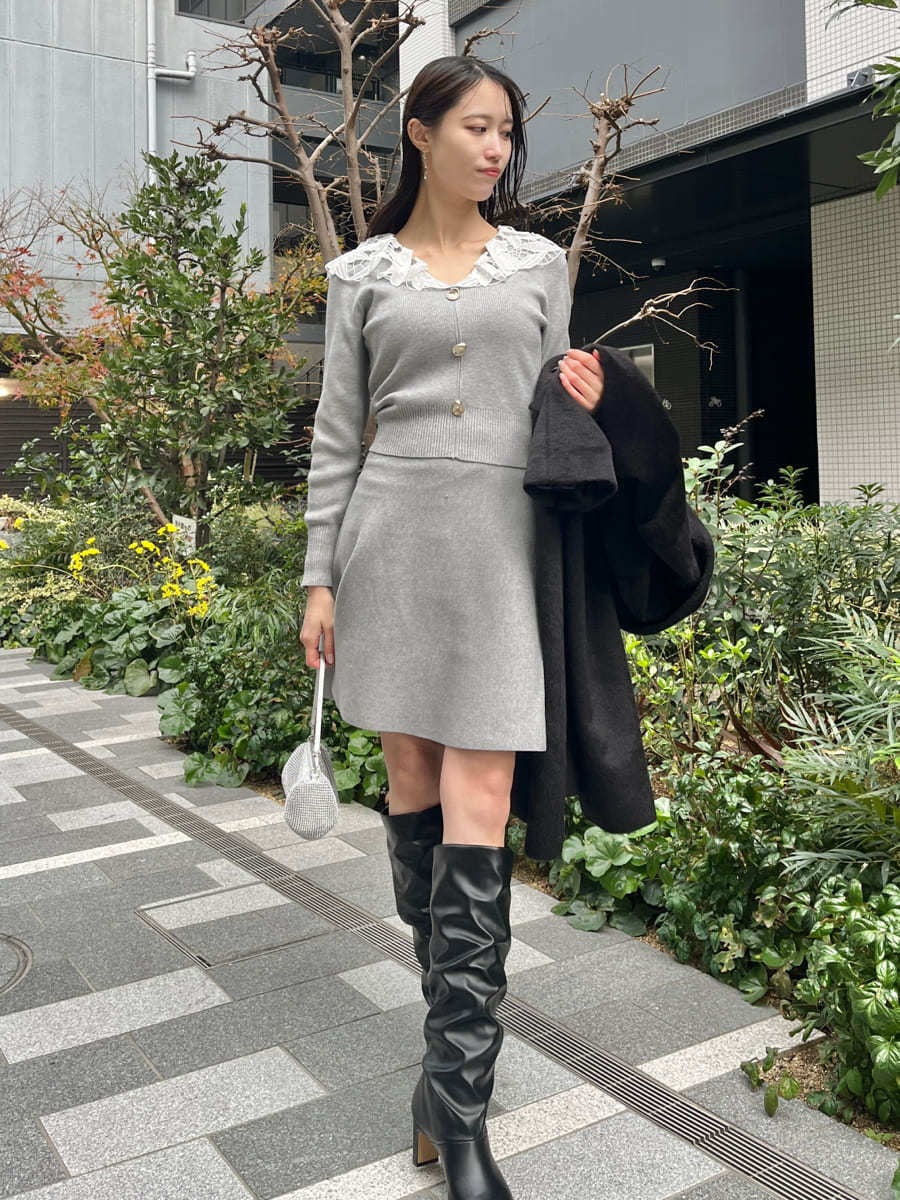 ブラック系のチェスターコート、グレー系のワンピースを着用したレディースの冬コーディネートの7枚目の写真
