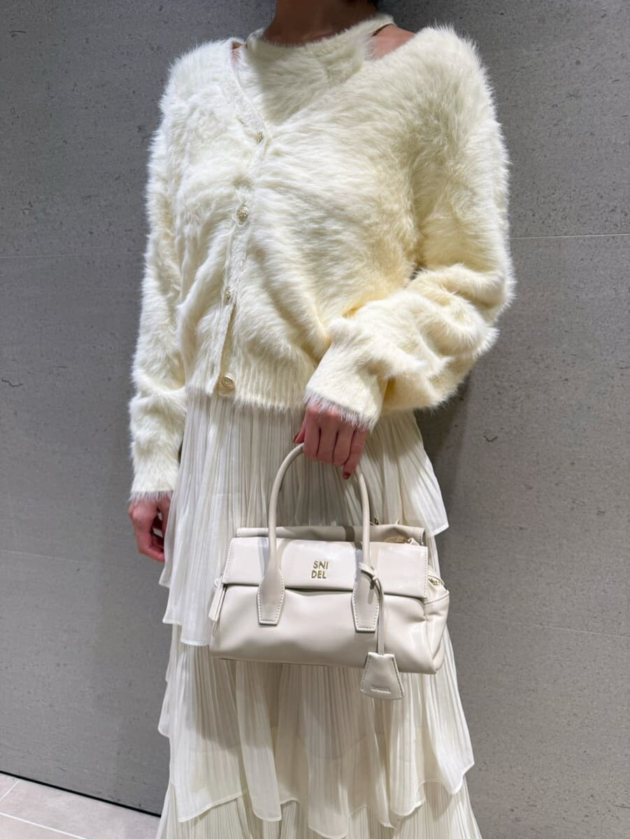 ブラウン系のブーツ、ホワイト系のスカート、イエロー系のニット/セーターを着用したレディースの秋コーディネートの5枚目の写真