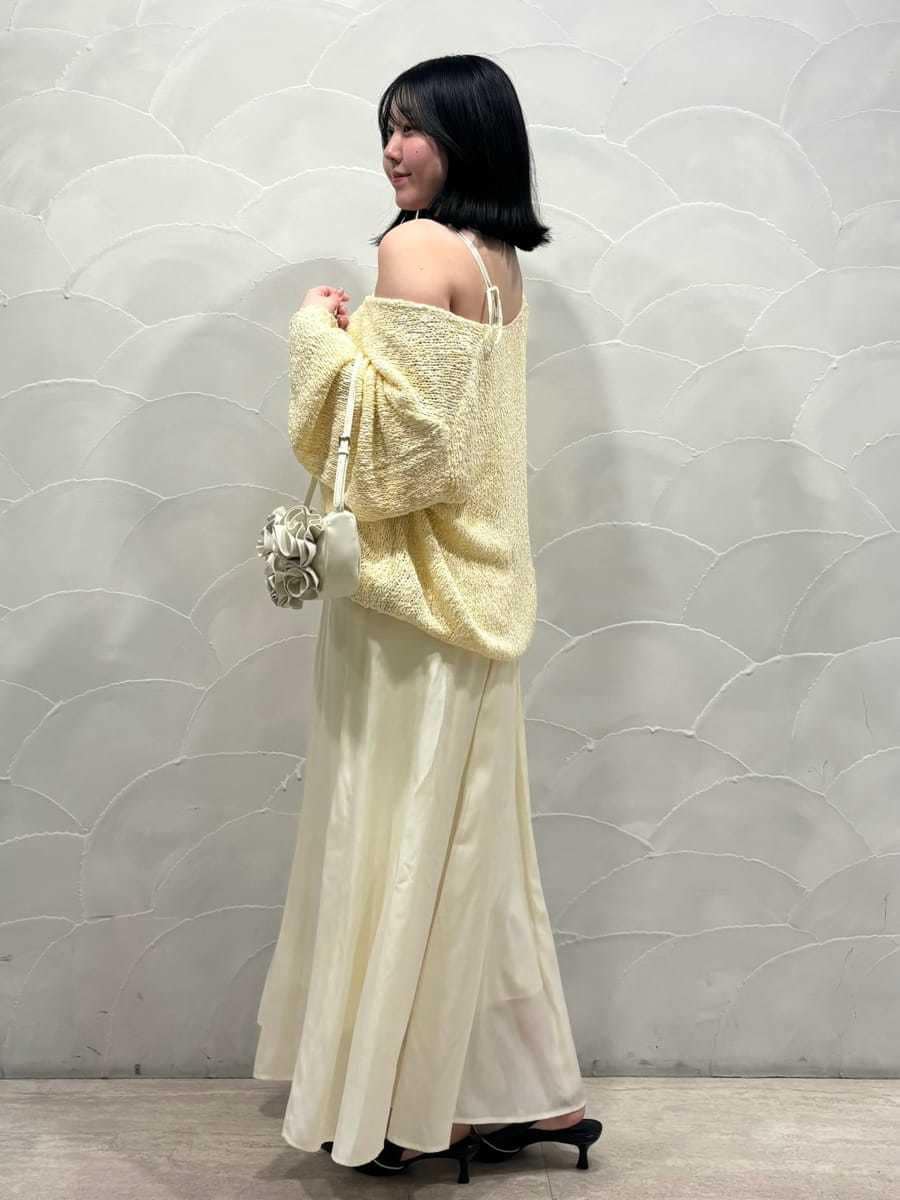 イエロー系のワンピース、ブラック系のパンプス、ホワイト系のハンドバッグを着用したレディースの冬コーディネートの2枚目の写真