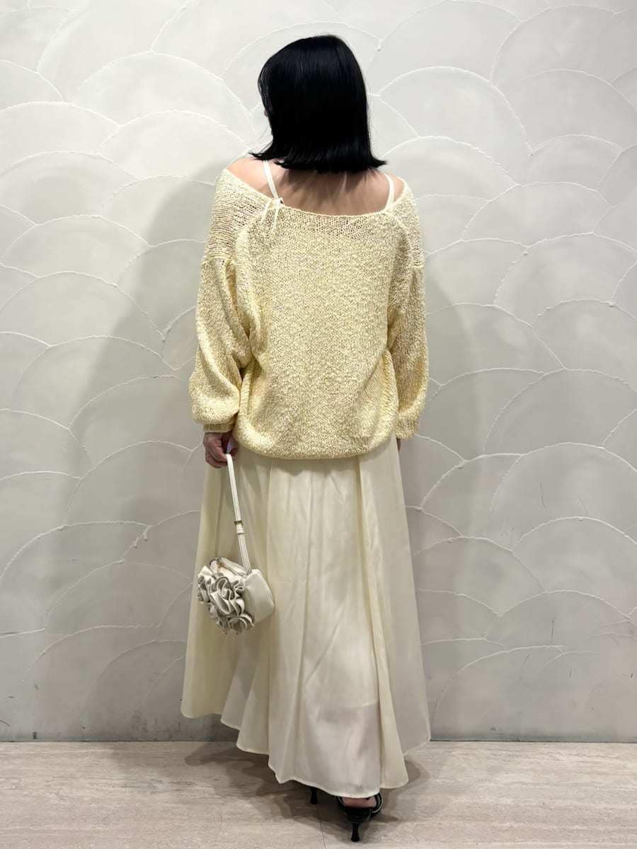 イエロー系のワンピース、ブラック系のパンプス、ホワイト系のハンドバッグを着用したレディースの冬コーディネートの3枚目の写真