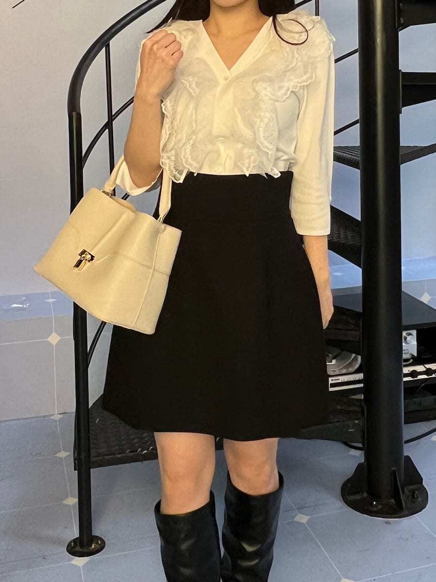 ブラック系のピーコート、ブラック系のスカート、ホワイト系のニット/セーターを着用したレディースの冬コーディネートの6枚目の写真