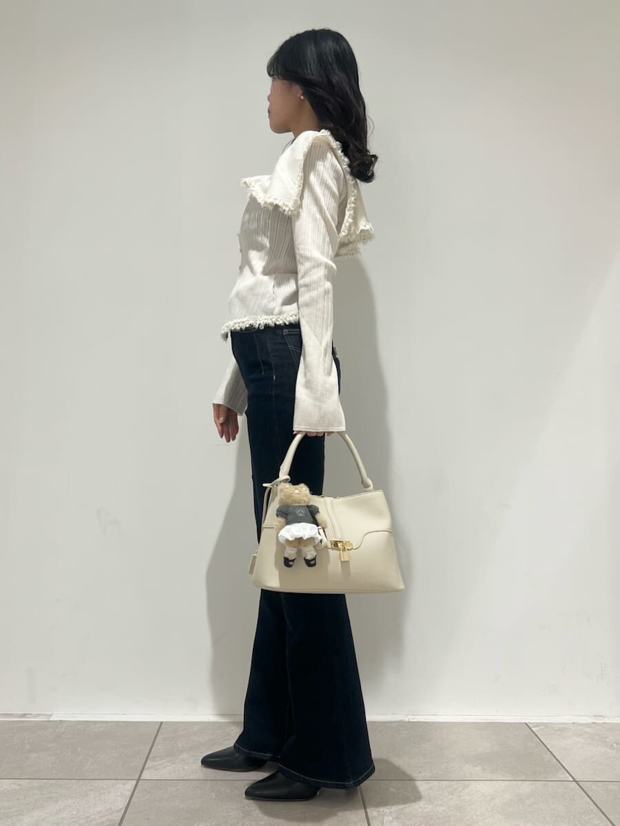 ブラック系のブーツ、ブルー系のその他パンツ、ホワイト系のニット/セーターを着用したレディースの冬コーディネートの2枚目の写真