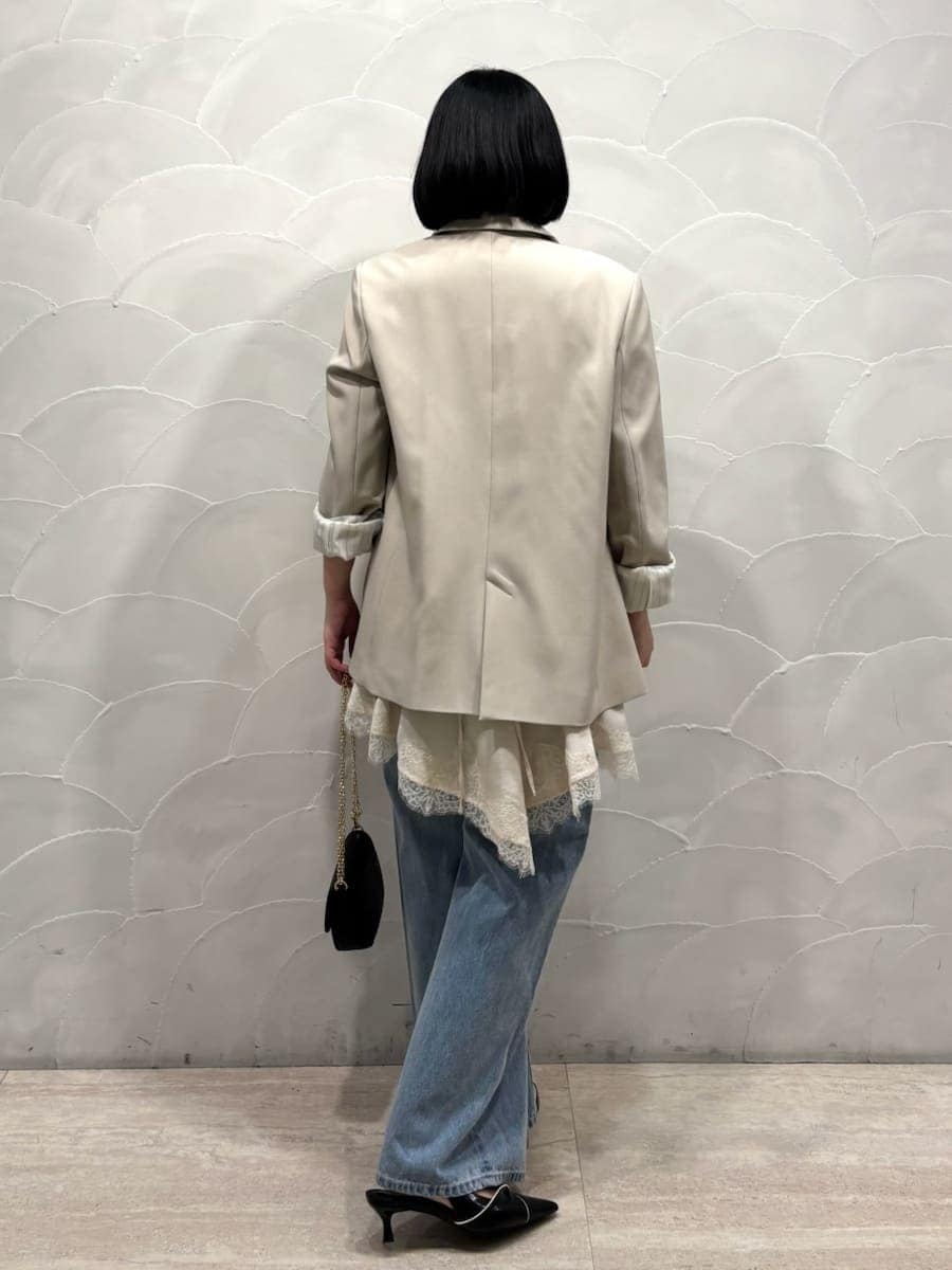 ベージュ系のテーラードジャケット、ブルー系のデニムパンツ、ホワイト系のキャミソールを着用したレディースの春コーディネートの3枚目の写真