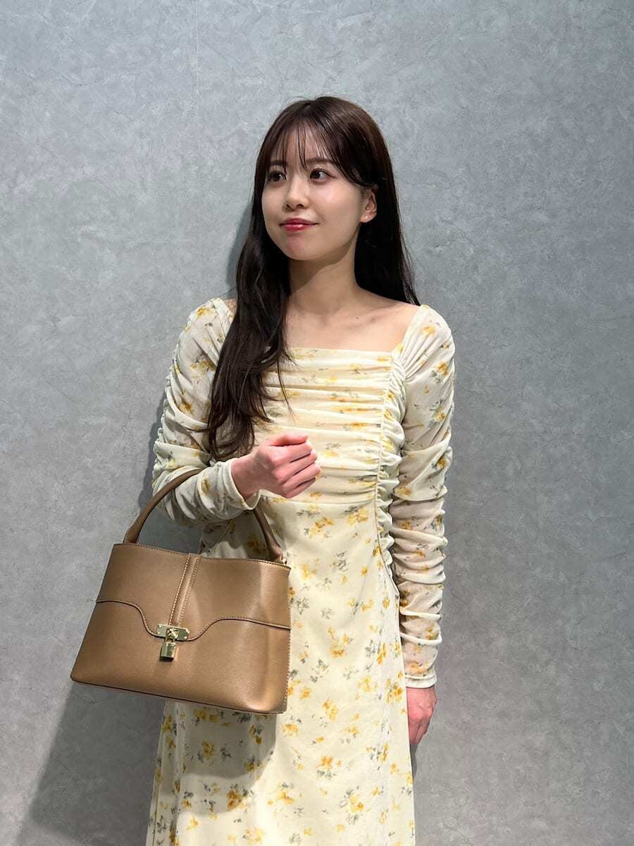 ベージュ系のブーツ、イエロー系のワンピース、イエロー系のハンドバッグを着用したレディースの冬コーディネートの2枚目の写真