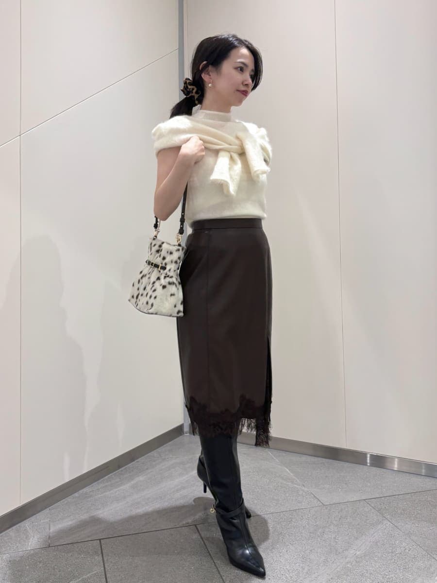 ブラウン系のスカート、ホワイト系のTシャツ/カットソー、ブラック系のブーツを着用したレディースの秋コーディネートの2枚目の写真