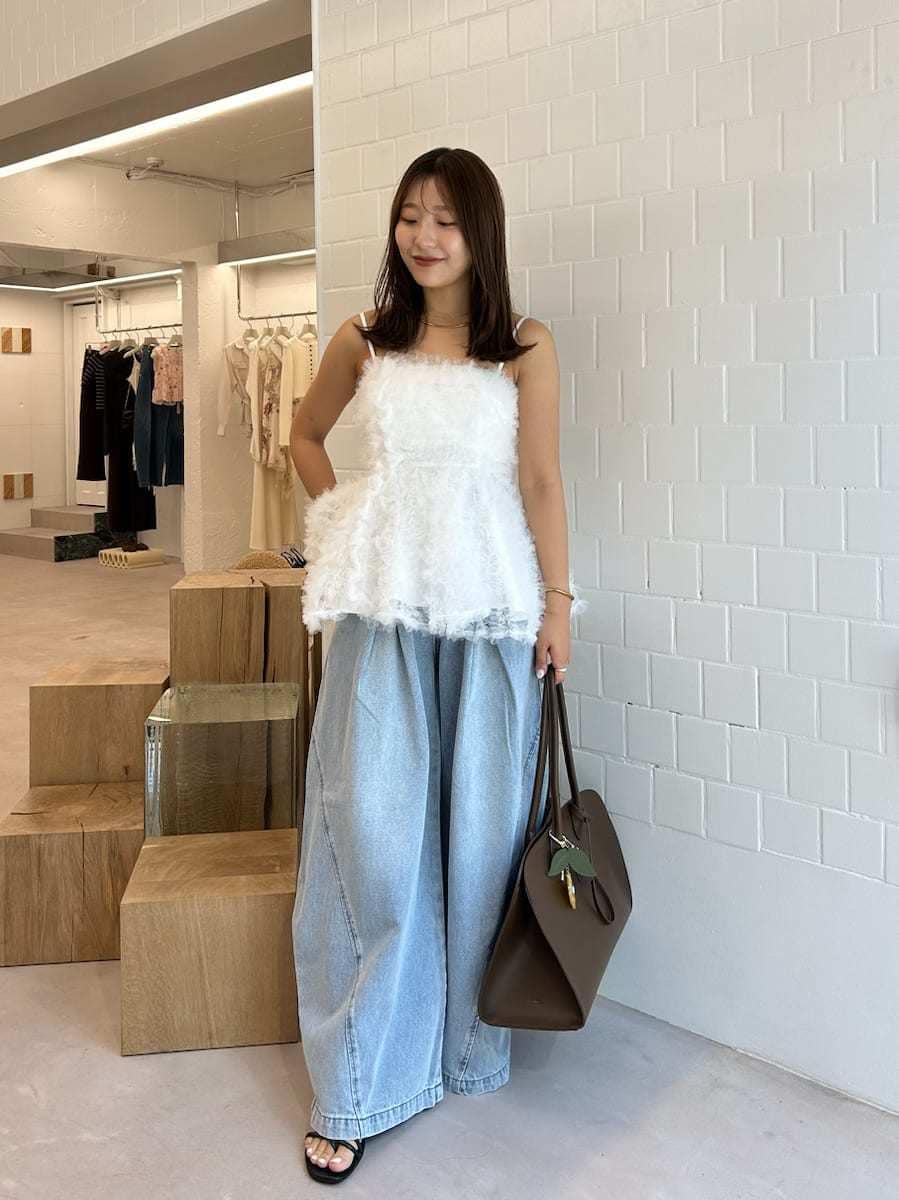 ブラック系のサンダル、ブルー系のデニムパンツ、ブラウン系のトートバッグを着用したレディースの夏コーディネートの4枚目の写真
